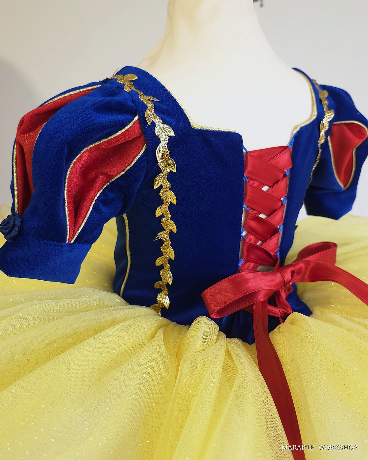 Close-up of Snow White inspired dress: royal blue velvet puff sleeves, gold leaf trim and red satin corset lacing - Mararte Workshop