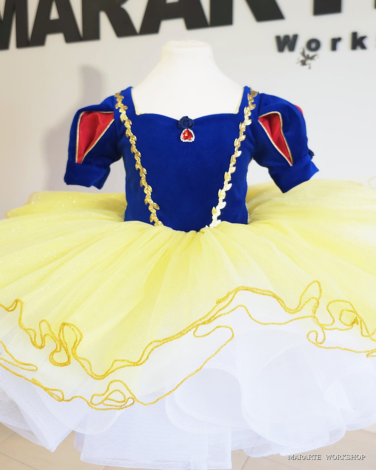 Snow White inspired princess tutu dress, front view: royal blue velvet bodice with gold leaf trim, red heart gem and yellow glitter tulle skirt - Mararte Workshop