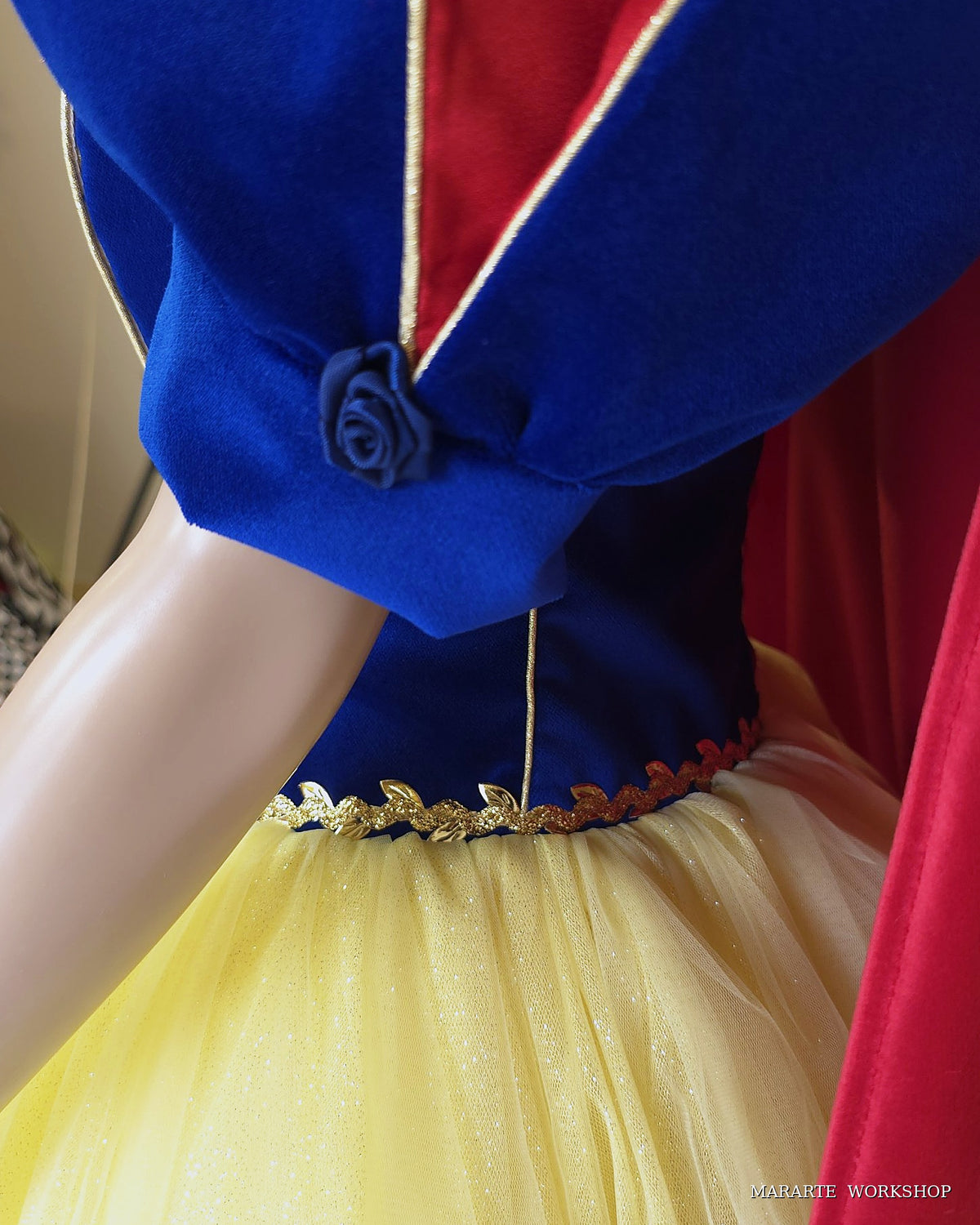 Detail of velvet puff sleeve with navy satin rose, gold piping and gold leaf waist trim on women's Snow White inspired dress - Mararte Workshop